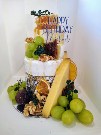 Cheese Wheel Cake Celebration Cheese Wheel Cake, wheels of cheese stacked with accompaniments dried figs, honey, honey comb, grapes, dried oranges, walnuts and fresh thyme.
